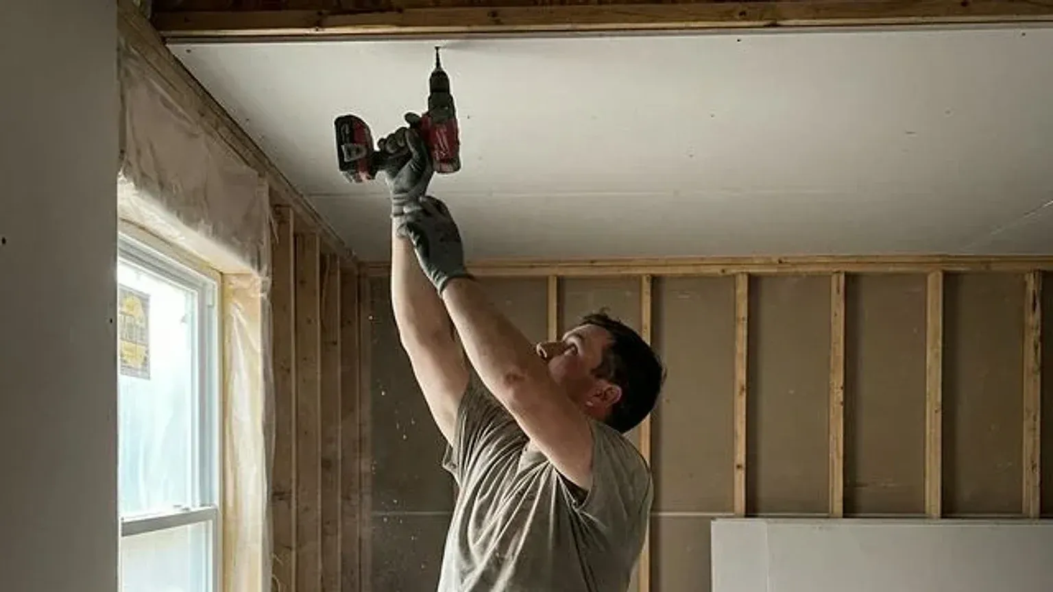 Drywall contractor fastening a ceiling panel on an Appleton, WI job site